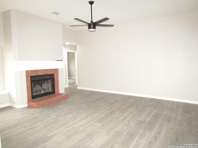 unfurnished living room featuring hardwood / wood-style floors, ceiling fan, and a tile fireplace