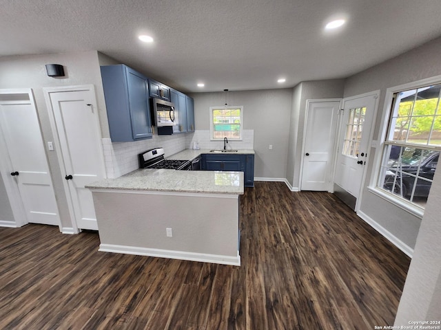 kitchen featuring stainless steel appliances, kitchen peninsula, dark wood-type flooring, decorative backsplash, and sink