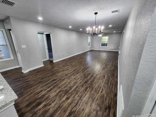 unfurnished dining area with ceiling fan with notable chandelier and dark wood-type flooring