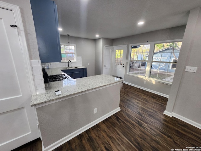 kitchen with sink, blue cabinets, range, backsplash, and hanging light fixtures