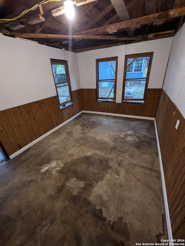 empty room with wood walls and concrete flooring