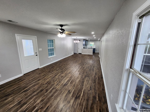 unfurnished living room featuring dark wood-type flooring, a textured ceiling, and ceiling fan