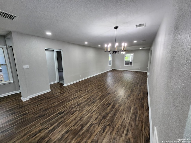 interior space with a textured ceiling, a chandelier, and dark hardwood / wood-style flooring