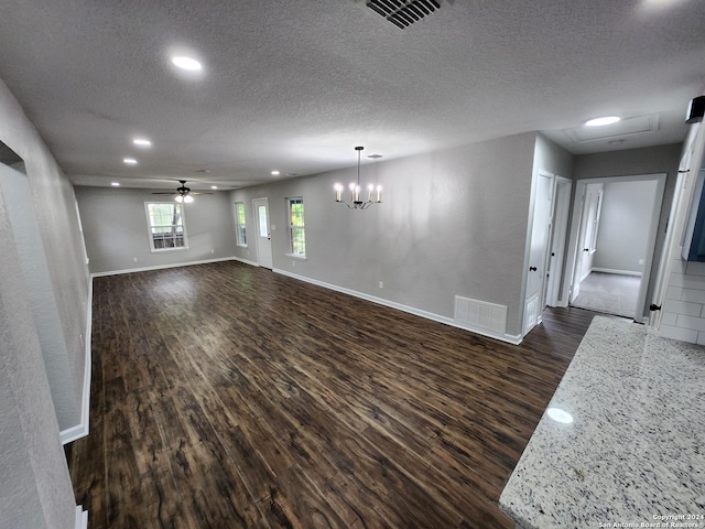 unfurnished living room featuring ceiling fan with notable chandelier, dark wood-type flooring, and a textured ceiling