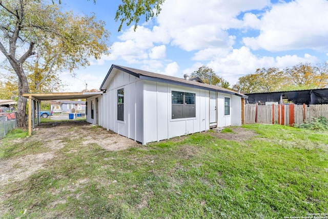 rear view of house with a lawn and a carport