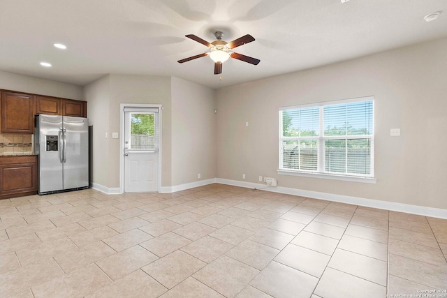 kitchen featuring ceiling fan, stainless steel fridge, light tile patterned flooring, and light stone countertops