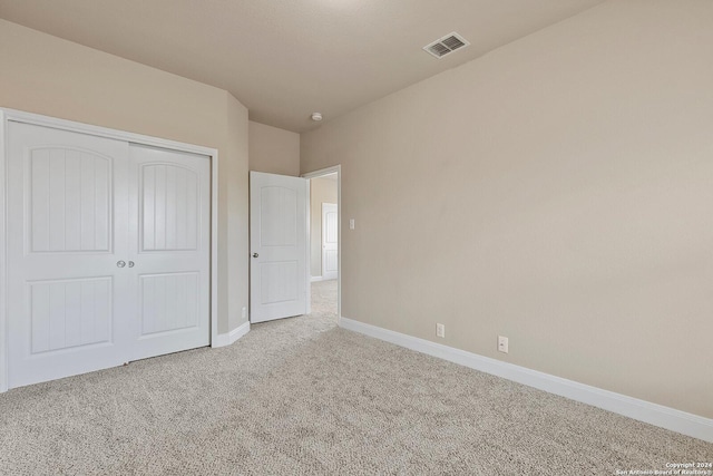 unfurnished bedroom with a closet and light colored carpet