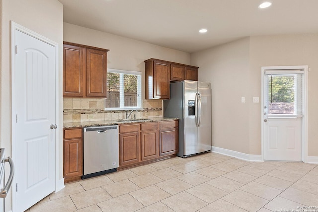 kitchen with light stone countertops, appliances with stainless steel finishes, backsplash, and plenty of natural light