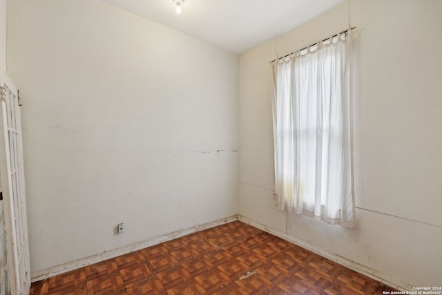 empty room featuring dark parquet floors and a healthy amount of sunlight