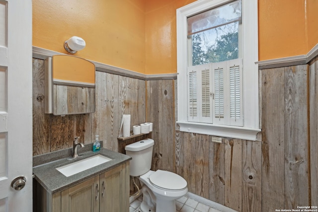 bathroom with tile patterned flooring, vanity, wood walls, and toilet