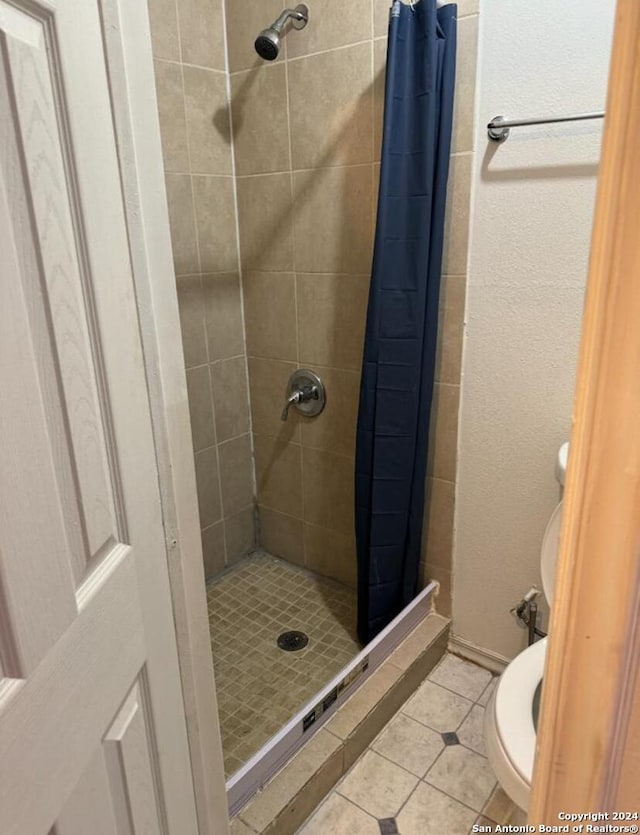 bathroom with toilet, tile patterned flooring, and a shower with shower curtain