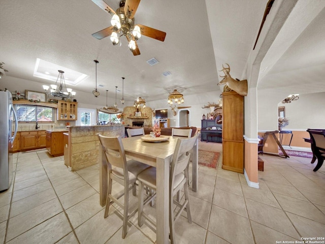 dining area featuring ceiling fan with notable chandelier, light tile patterned flooring, and a textured ceiling