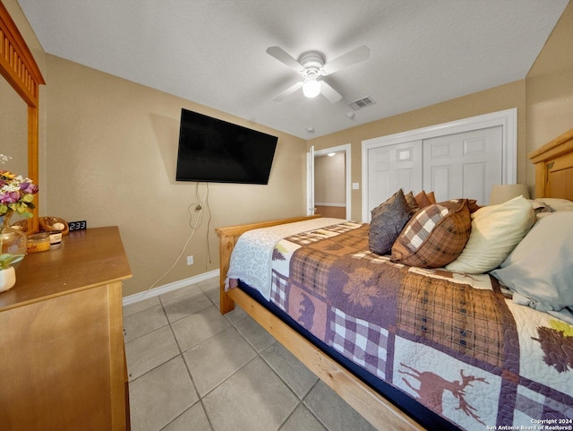 bedroom featuring a textured ceiling, a closet, ceiling fan, and light tile patterned flooring