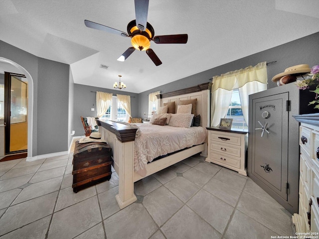 bedroom with a textured ceiling, lofted ceiling, light tile patterned flooring, and ceiling fan with notable chandelier