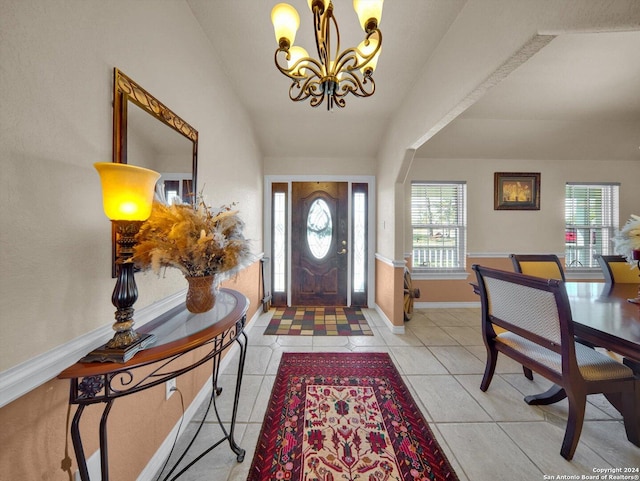 foyer entrance with a wealth of natural light, light tile patterned floors, a chandelier, and vaulted ceiling