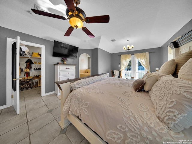 bedroom with ceiling fan with notable chandelier, a walk in closet, access to exterior, light tile patterned flooring, and a closet