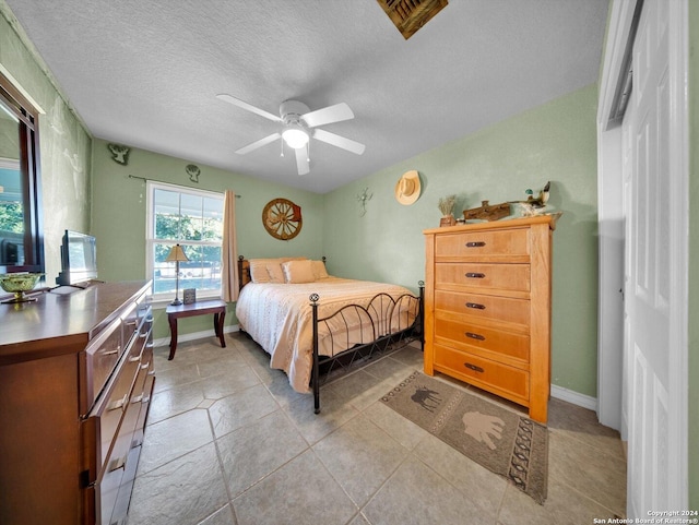 bedroom featuring light tile patterned floors, a textured ceiling, and ceiling fan