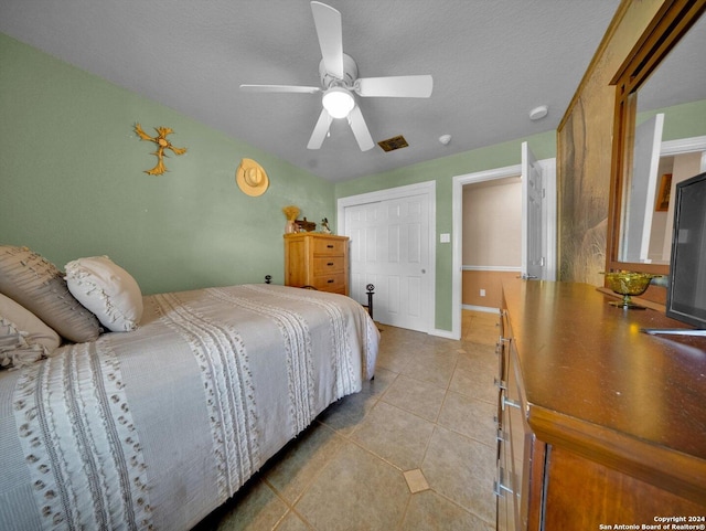 tiled bedroom with a textured ceiling, a closet, and ceiling fan