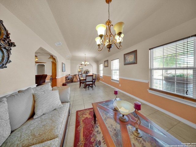 tiled living room with ceiling fan with notable chandelier and lofted ceiling