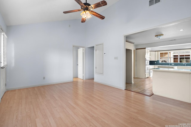 unfurnished living room with ceiling fan, light wood-type flooring, and high vaulted ceiling