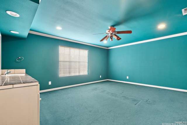 interior space with ceiling fan, sink, carpet floors, and ornamental molding