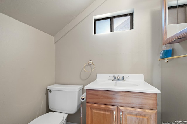 bathroom featuring vanity, vaulted ceiling, and toilet