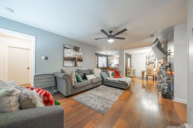 living room with wood-type flooring and ceiling fan with notable chandelier