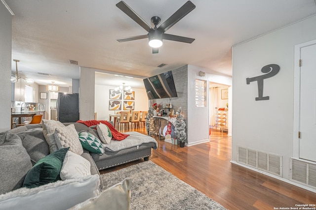 living room with ceiling fan with notable chandelier, wood-type flooring, and sink