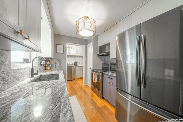 kitchen featuring white cabinets, sink, dark stone countertops, decorative light fixtures, and stainless steel appliances