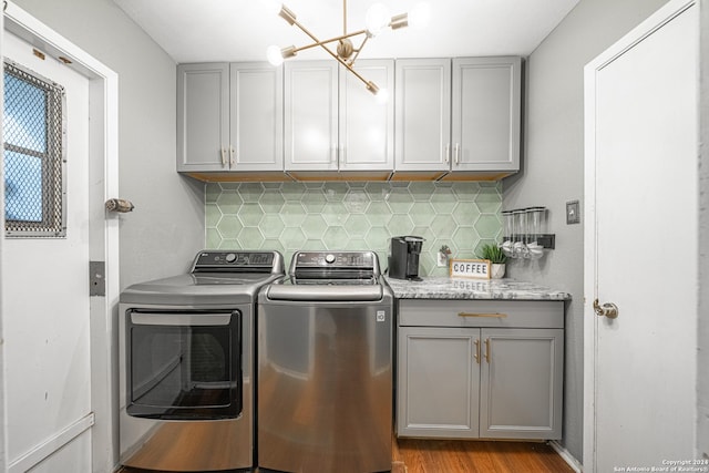 washroom with light hardwood / wood-style floors, washer and clothes dryer, cabinets, and a notable chandelier