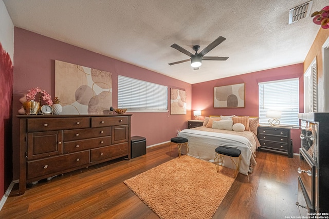 bedroom with a textured ceiling, multiple windows, and dark wood-type flooring