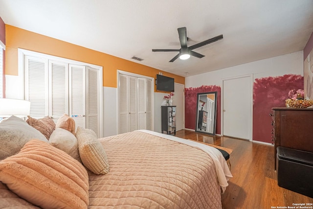 bedroom featuring ceiling fan, wood-type flooring, and multiple closets