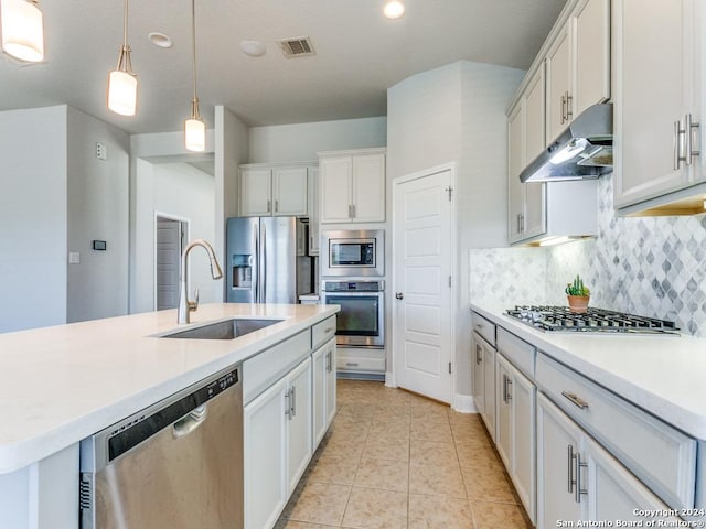 kitchen featuring a kitchen island with sink, white cabinets, sink, decorative light fixtures, and stainless steel appliances