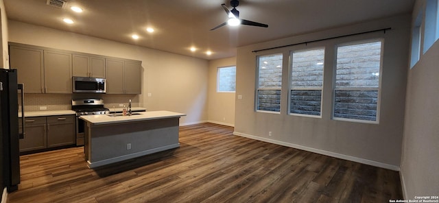 kitchen with ceiling fan, sink, stainless steel appliances, tasteful backsplash, and a kitchen island with sink