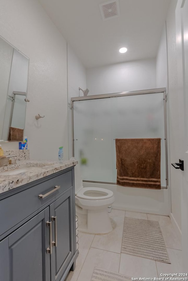 full bathroom with tile patterned flooring, vanity, bath / shower combo with glass door, and toilet