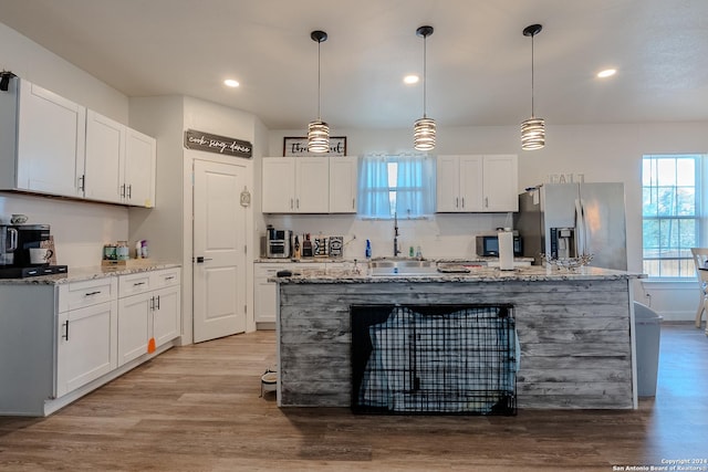 kitchen featuring white cabinets, stainless steel fridge, and hanging light fixtures