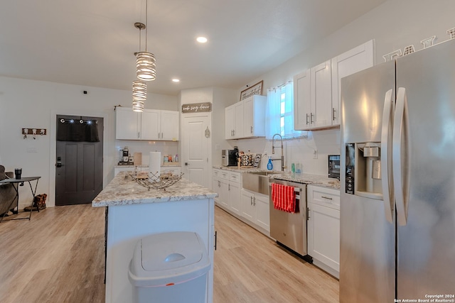 kitchen featuring hanging light fixtures, light wood-type flooring, appliances with stainless steel finishes, a kitchen island, and white cabinetry