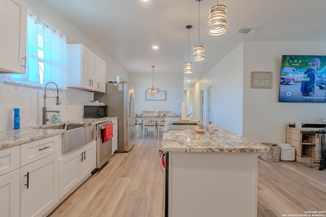 kitchen with pendant lighting, white cabinets, stainless steel dishwasher, light hardwood / wood-style floors, and a kitchen island