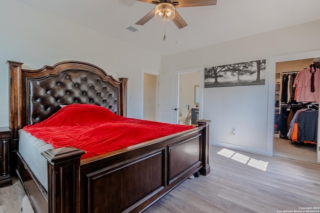 bedroom featuring a closet, a walk in closet, light hardwood / wood-style floors, and ceiling fan