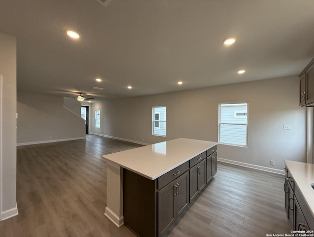 kitchen featuring hardwood / wood-style floors, dark brown cabinets, a kitchen island, and ceiling fan