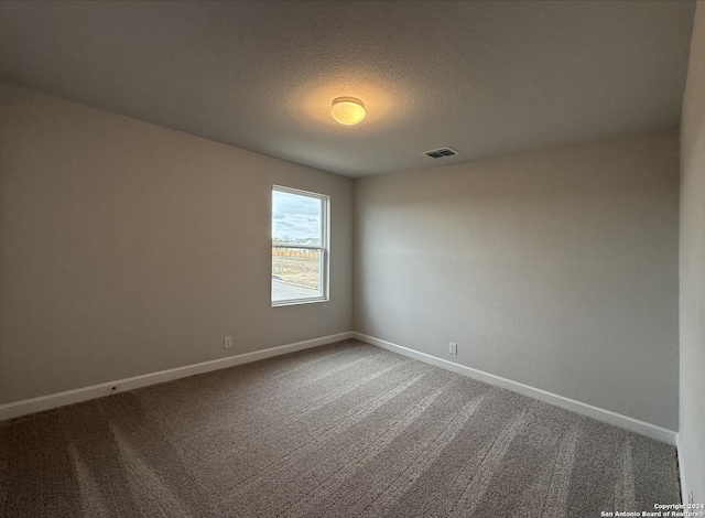 carpeted spare room with a textured ceiling