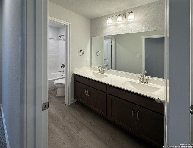 full bathroom featuring a textured ceiling, vanity, shower / washtub combination, hardwood / wood-style flooring, and toilet