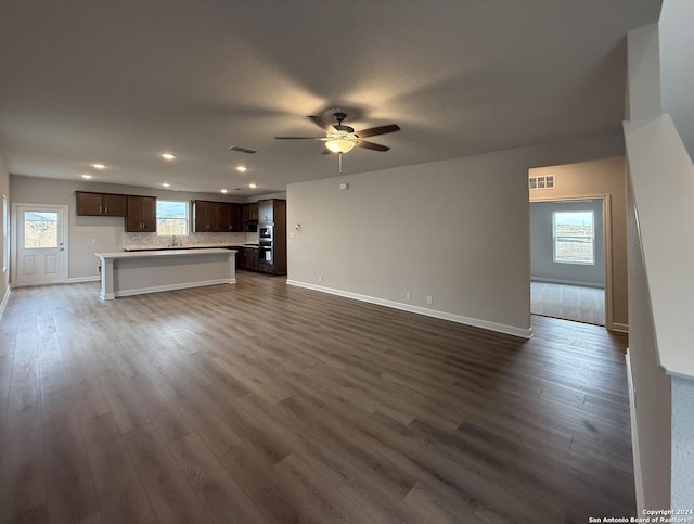 unfurnished living room with ceiling fan, dark hardwood / wood-style flooring, and sink