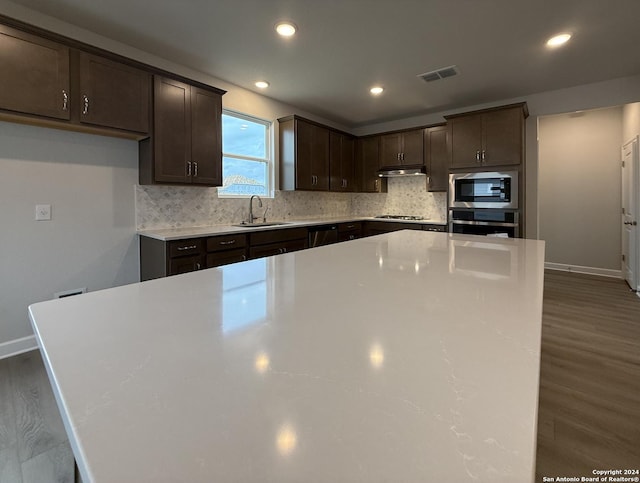 kitchen featuring a center island, sink, stainless steel appliances, and dark wood-type flooring