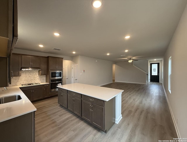 kitchen featuring backsplash, stainless steel appliances, sink, light hardwood / wood-style floors, and a kitchen island