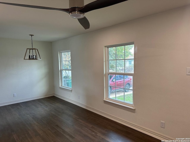 unfurnished room featuring ceiling fan with notable chandelier and dark hardwood / wood-style flooring