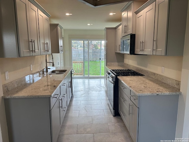 kitchen with gray cabinetry, light stone counters, and stainless steel appliances