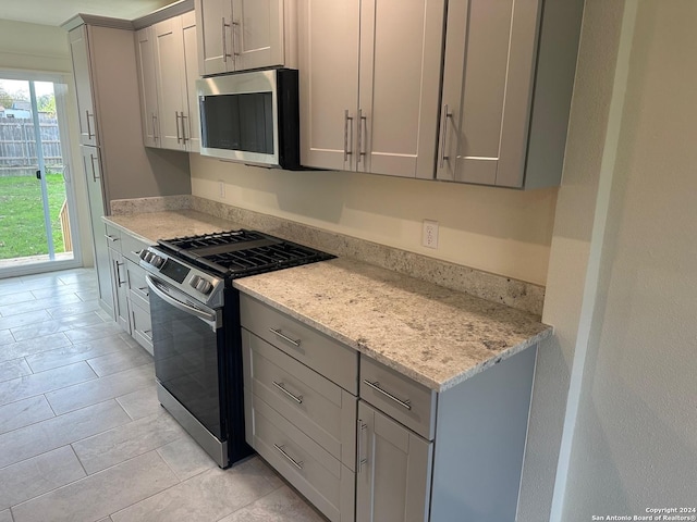 kitchen featuring appliances with stainless steel finishes, gray cabinets, and light stone counters