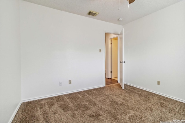 spare room with baseboards, carpet, visible vents, and a textured ceiling