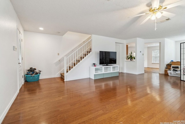 unfurnished living room with ceiling fan, hardwood / wood-style floors, and a textured ceiling